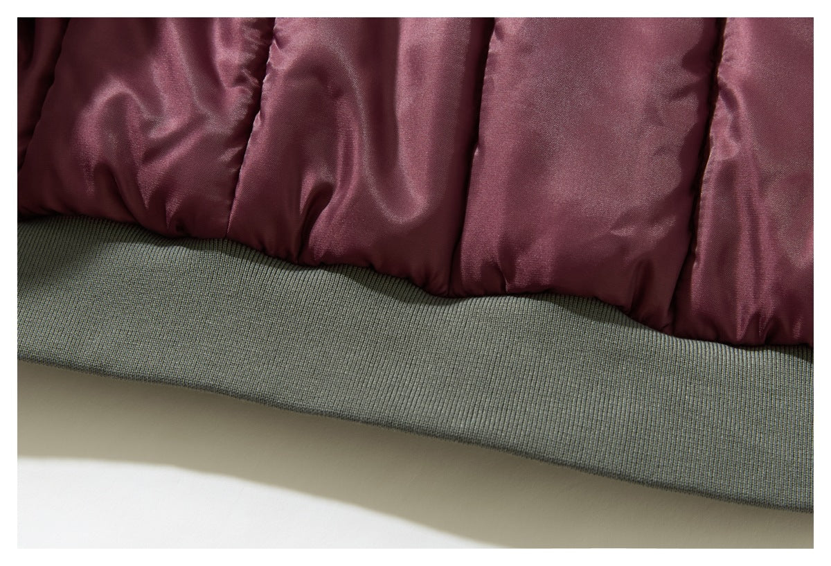 Close-up of a burgundy padded garment with a wide gray ribbed hem.