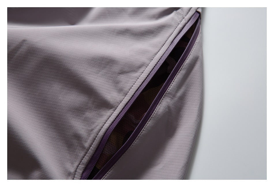 Close-up of a purple-trimmed zip opening on mauve-gray pants, revealing dark mesh lining.