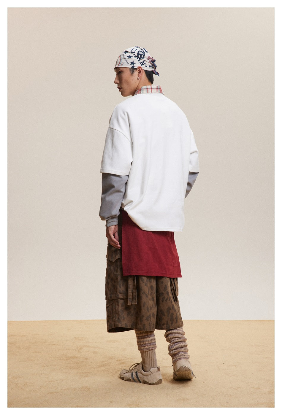 Back view of a model wearing an oversized white short-sleeve sweatshirt over gray sleeves.