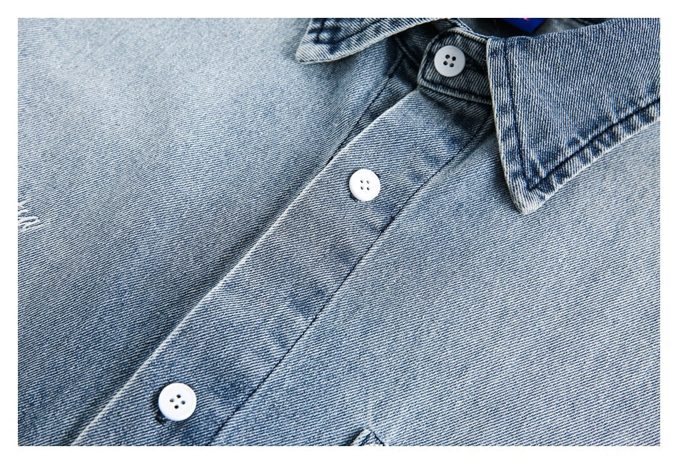 Close-up of a light blue denim shirt collar and front placket with white buttons.