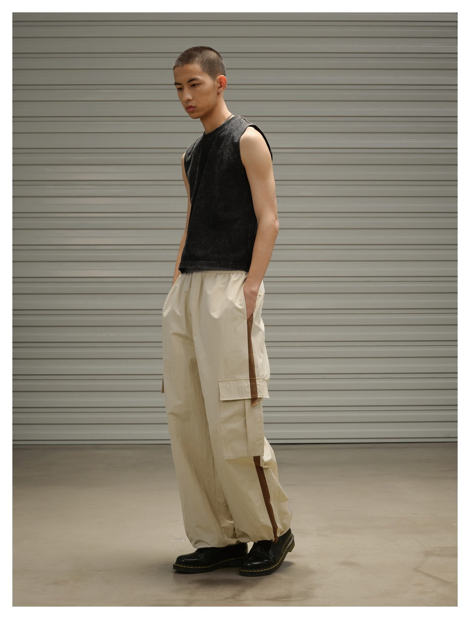 Model wearing loose beige cargo pants with brown side stripes, shown in a three-quarter view.