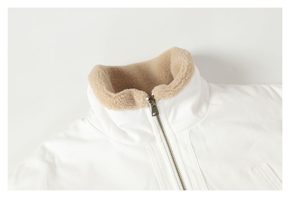 Close-up of an off-white jacket with a full metal zipper and a tall collar lined in tan fleece.