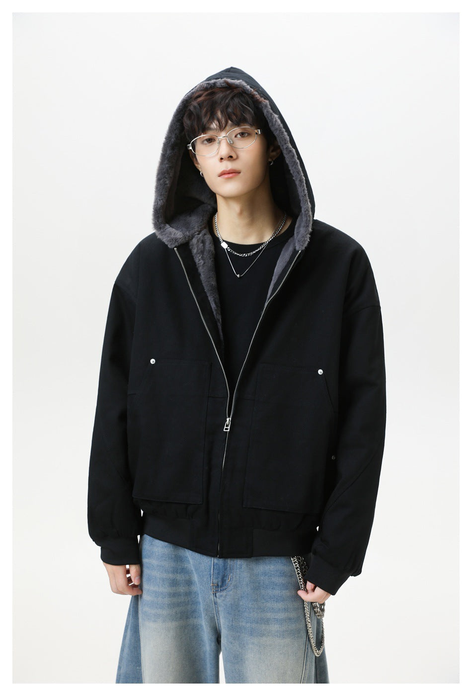 Model wearing a black hooded jacket with gray plush lining, silver zipper, ribbed cuffs, and two large front pockets.