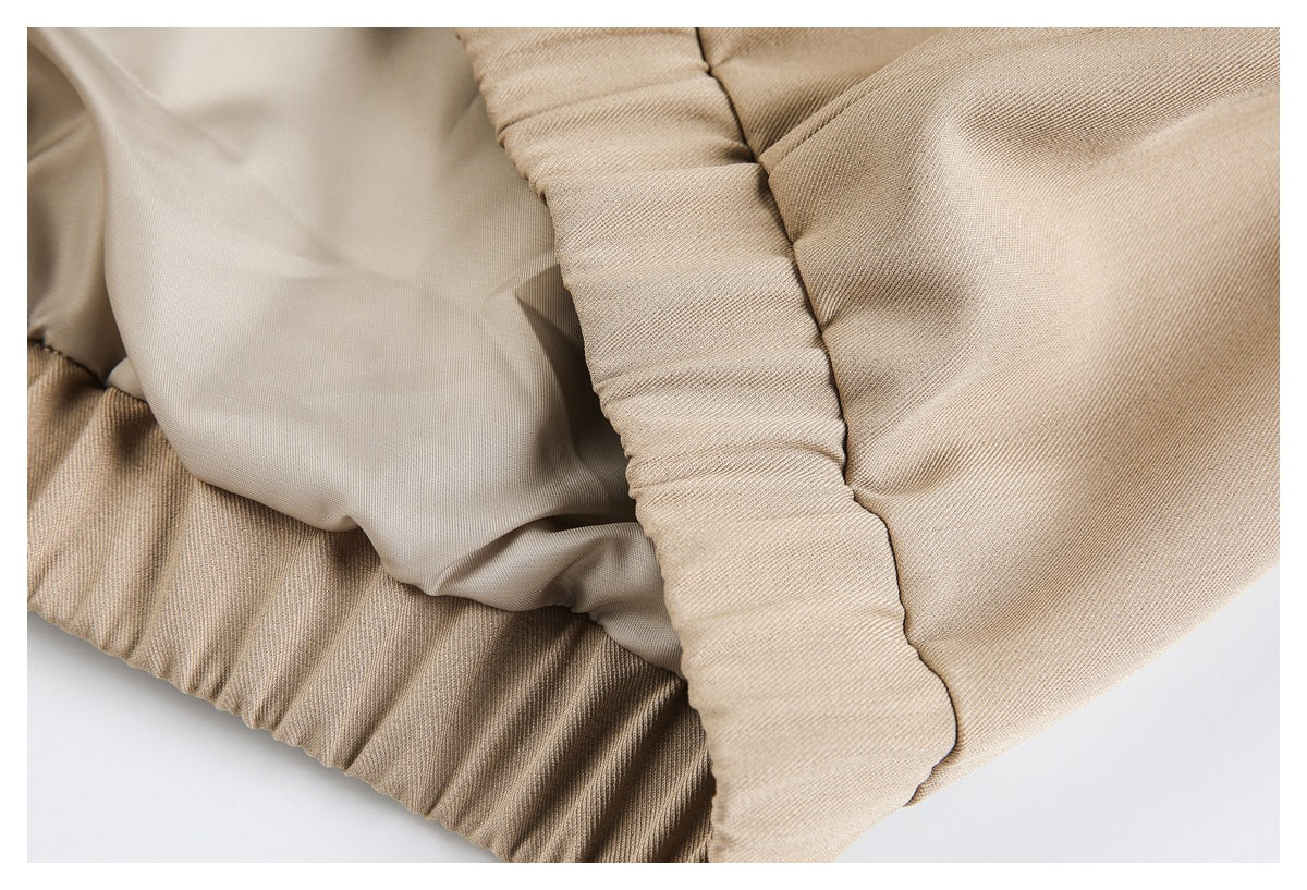 Close-up of beige garment with smooth pale lining and gathered stitching along a padded-looking edge.