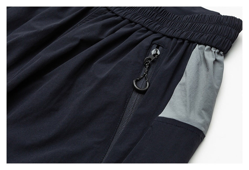Close-up of a vertical zip pocket beside a gray panel on navy pants.
