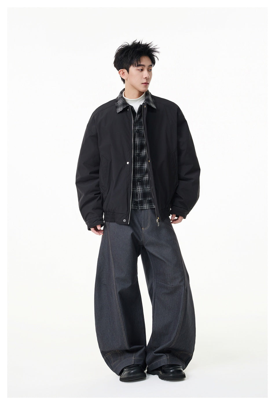 Full-length model wearing a black jacket with a plaid collar, plaid shirt, and wide-leg dark jeans.