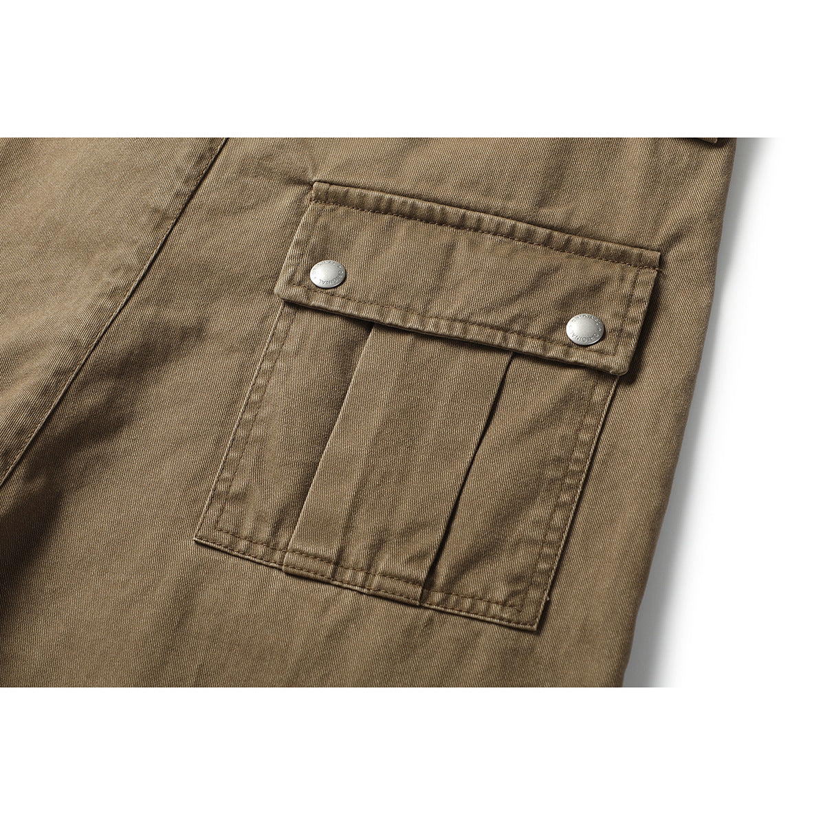 Close-up of a tan-brown trouser cargo pocket with a flap secured by two metal buttons.