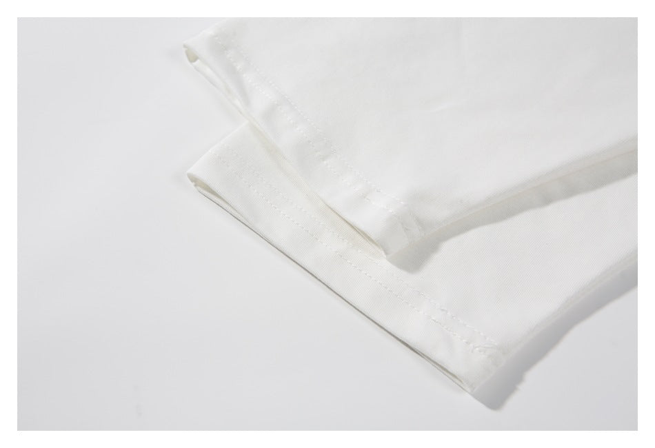 Close-up of a folded white garment showing its stitched hem and fabric texture.