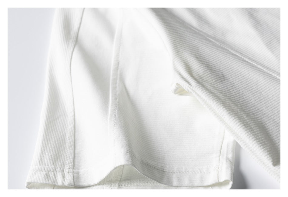 Close-up of a white ribbed knit garment hem and stitched seam.