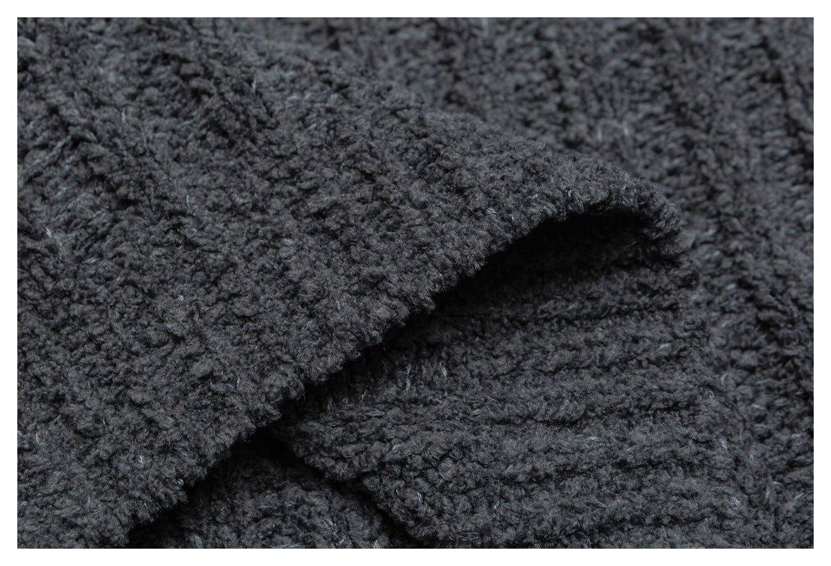 Close-up of overlapping edges on a dark charcoal knit garment, highlighting its thick textured fabric.