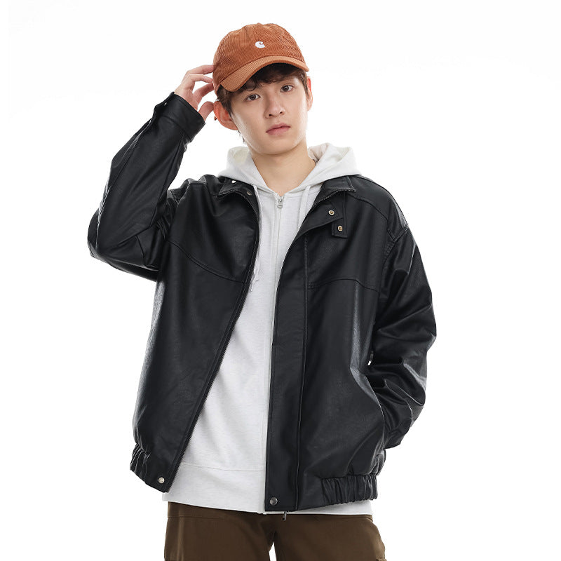 Model wearing a black stand-collar jacket with snap details and an elastic hem over a white hoodie.