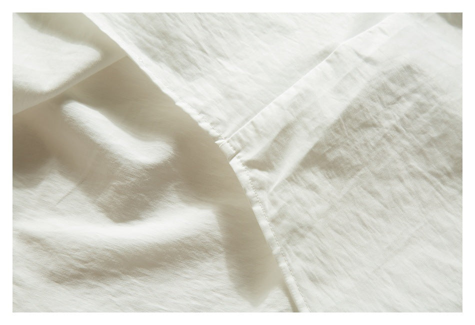 Close-up of white garment fabric showing a curved stitched seam and folded edge.