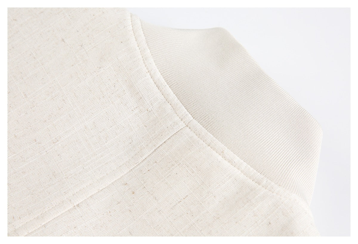 Close-up of off-white woven fabric showing a curved stitched seam and subtle flecks.