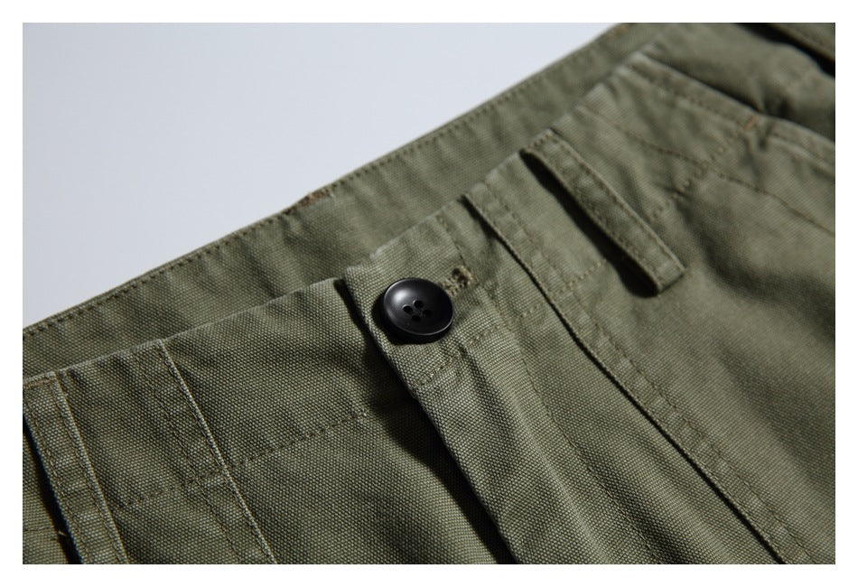 Close-up of the olive trouser waistband with a black button, belt loops, and fly stitching.