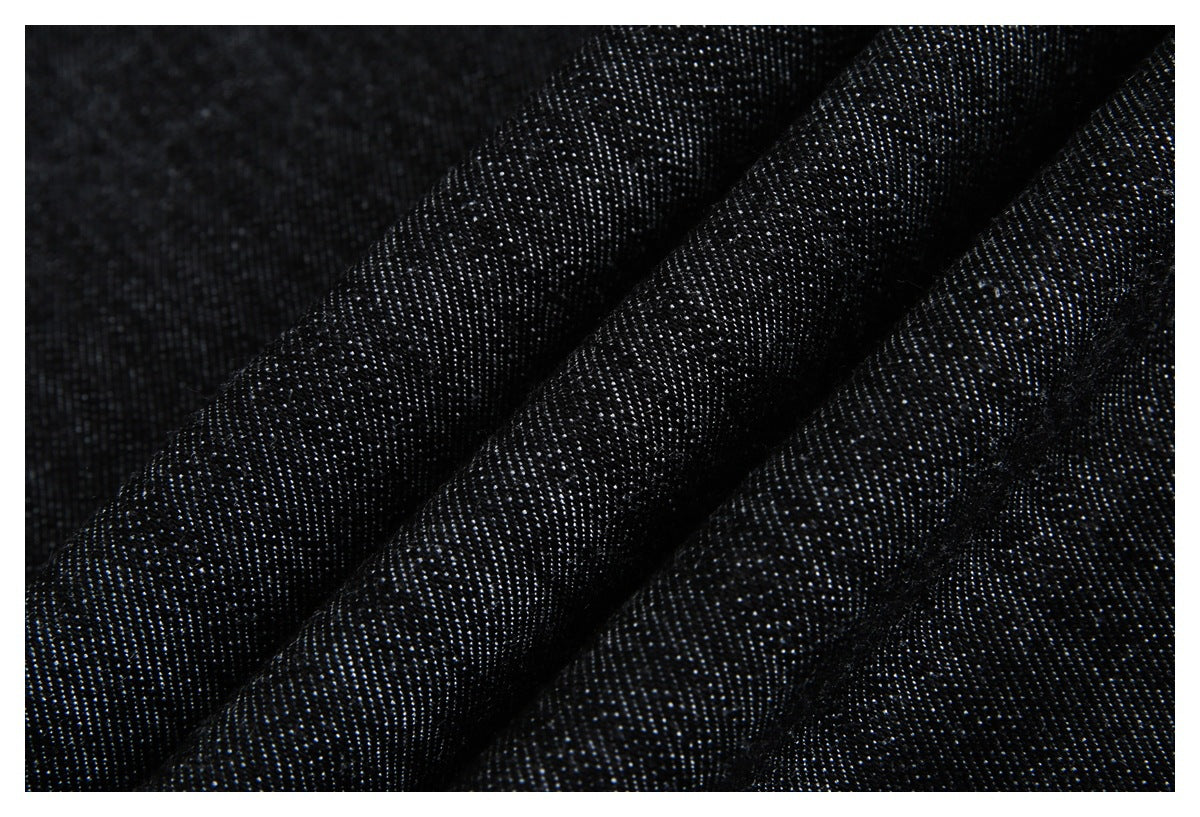 Close-up of dark navy-black woven fabric with a fine, subtly speckled texture and diagonal folds.