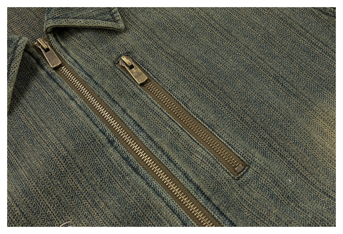 Close-up of a textured olive-gray garment with two antique-brass zippers.