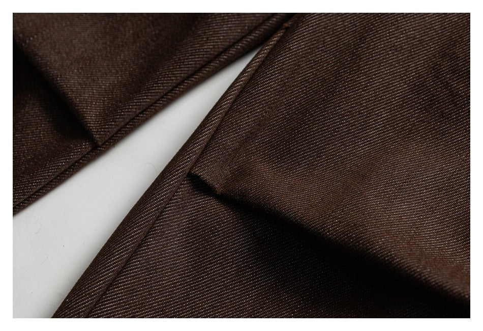 Close-up of brown trousers showing overlapping fabric panels, a folded edge, and stitching.