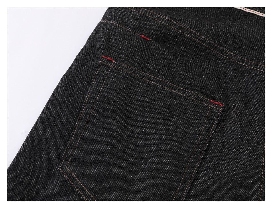Close-up of a black jeans back pocket with brown stitching and small red bar-tack accents.