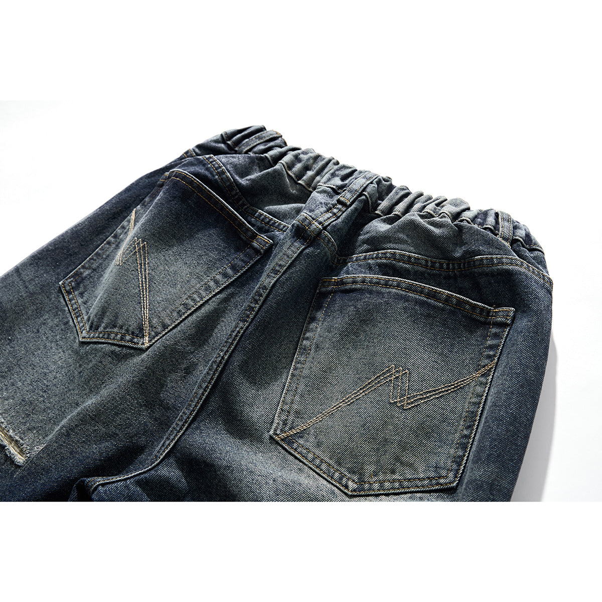 Close-up of the back of dark washed jeans with two stitched patch pockets and a gathered waistband.