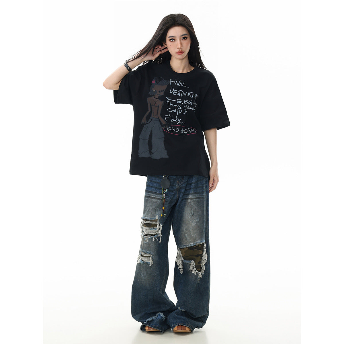 Model wearing an oversized black T-shirt with a cartoon figure and handwritten-style text on the front.