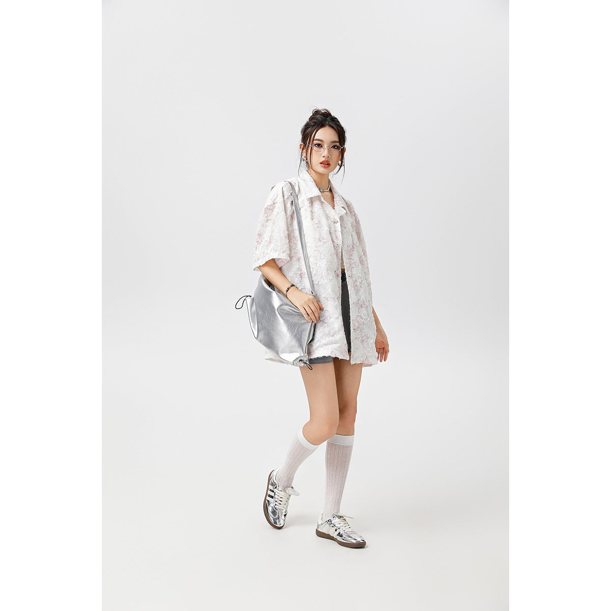 Model wearing an oversized white short-sleeve button-up shirt with a pale pink floral pattern and shorts.