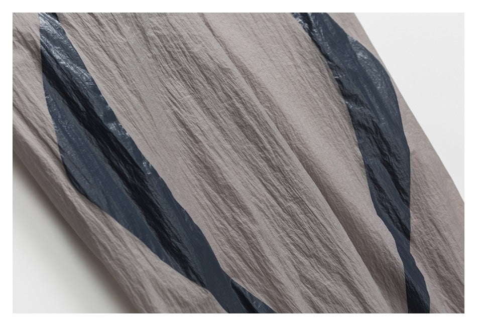 Close-up of gray crinkled fabric with broad dark graphic stripes.