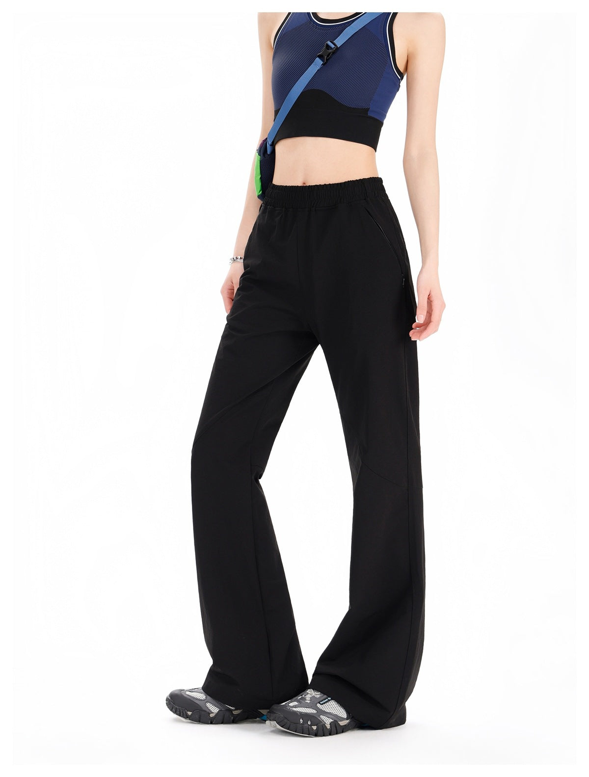Side angle of woman wearing black flared pants with elastic waist and knee seam, styled with a crop top