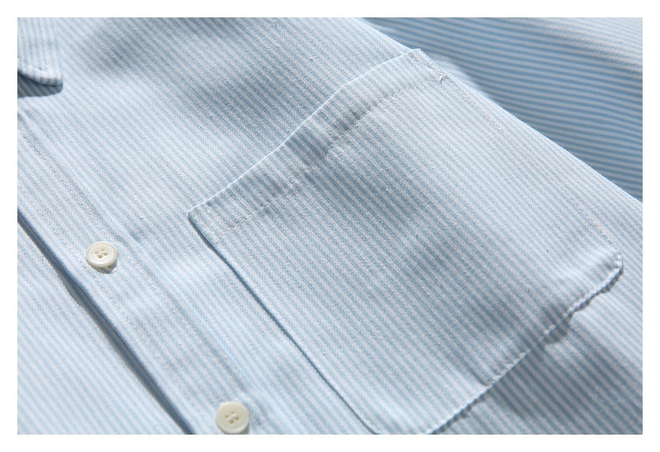 Close-up of the striped shirt's chest pocket and adjacent white buttons.