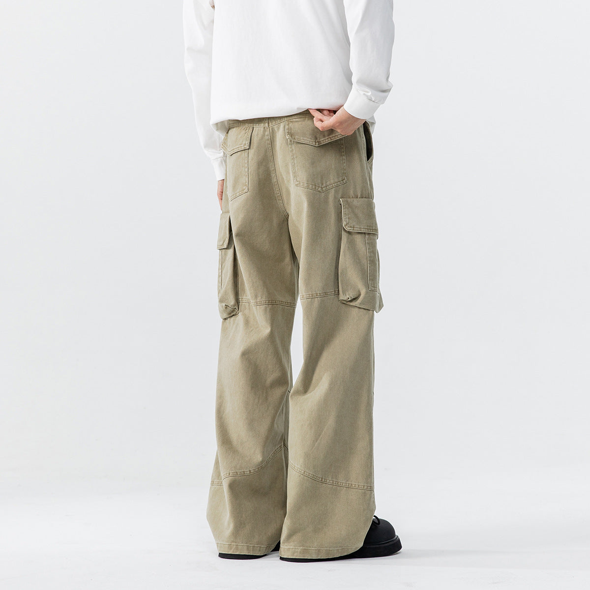 Back view of a model wearing light khaki wide-leg cargo pants with rear and oversized side flap pockets.