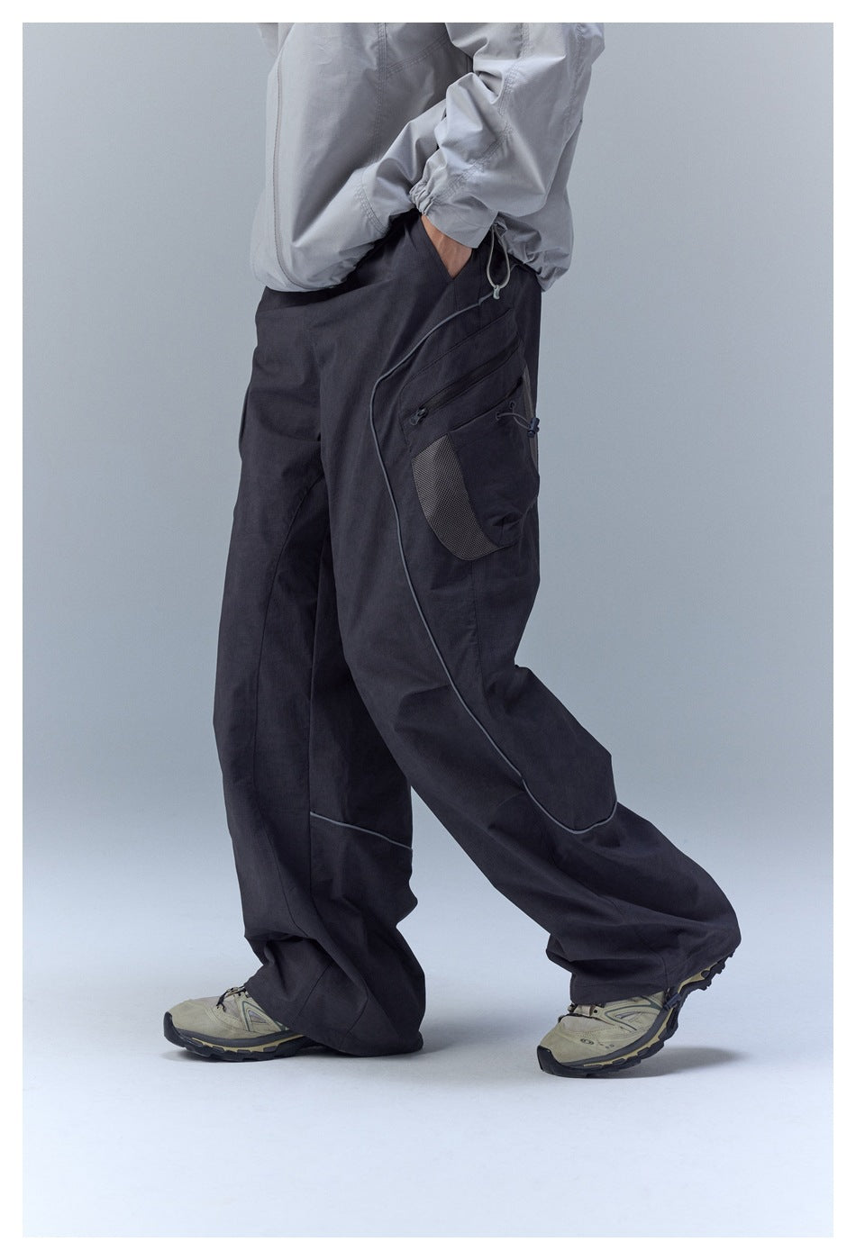 Side view highlighting the black pants' layered cargo pockets, mesh panel, and curved piping.