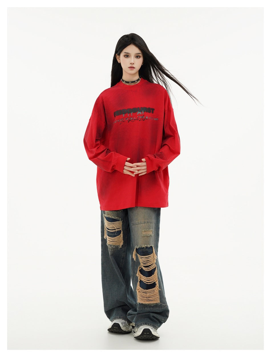 Model wearing an oversized red graphic long-sleeve shirt with distressed wide-leg jeans, shown full length.
