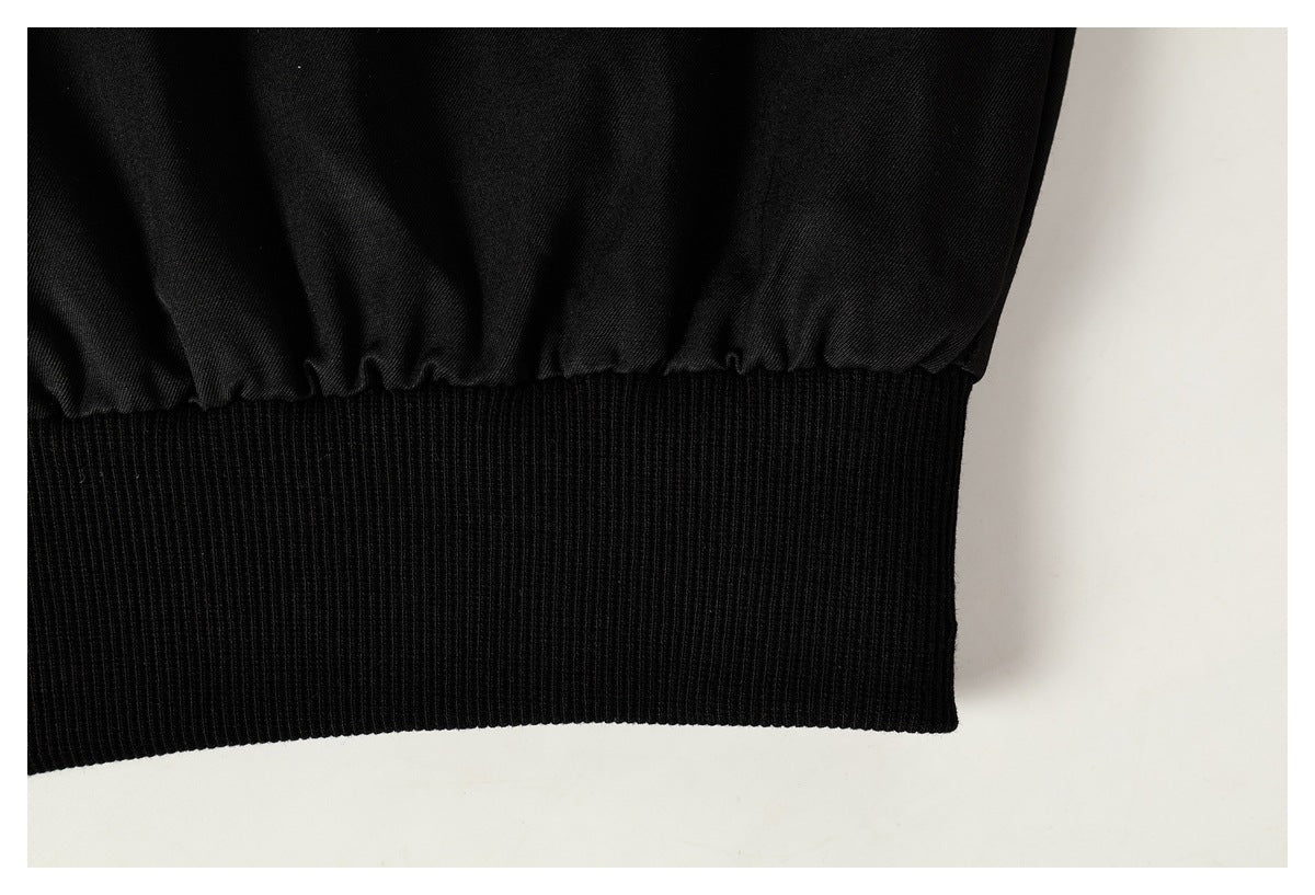 Close-up of a black ribbed waistband gathered against the jacket fabric.