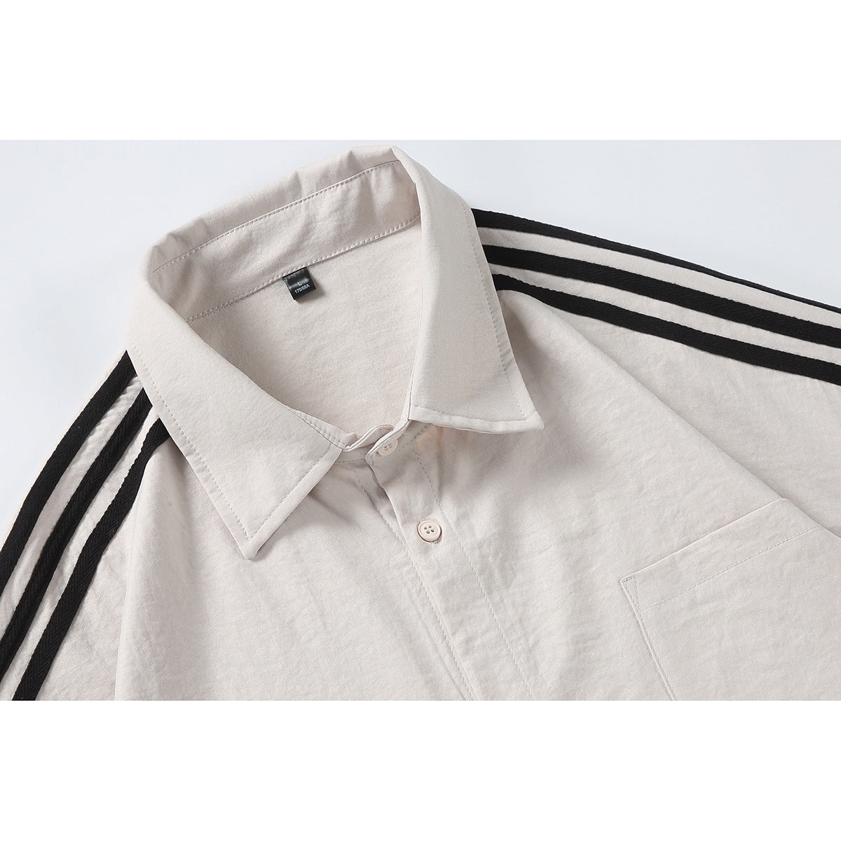 Close-up of an off-white shirt collar, buttons, chest pocket edge, and black shoulder stripes.