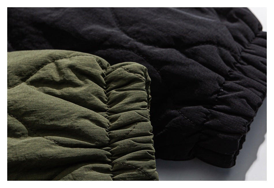 Close-up of gathered elastic cuffs and quilted fabric on olive and black jackets.