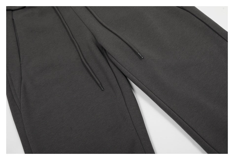 Close-up of charcoal pants showing two dark drawstrings and diagonal fabric panels.