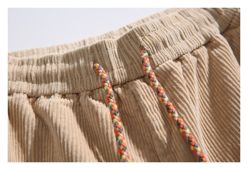 Close-up of tan corduroy shorts with an elastic waistband and multicolored braided drawstrings.