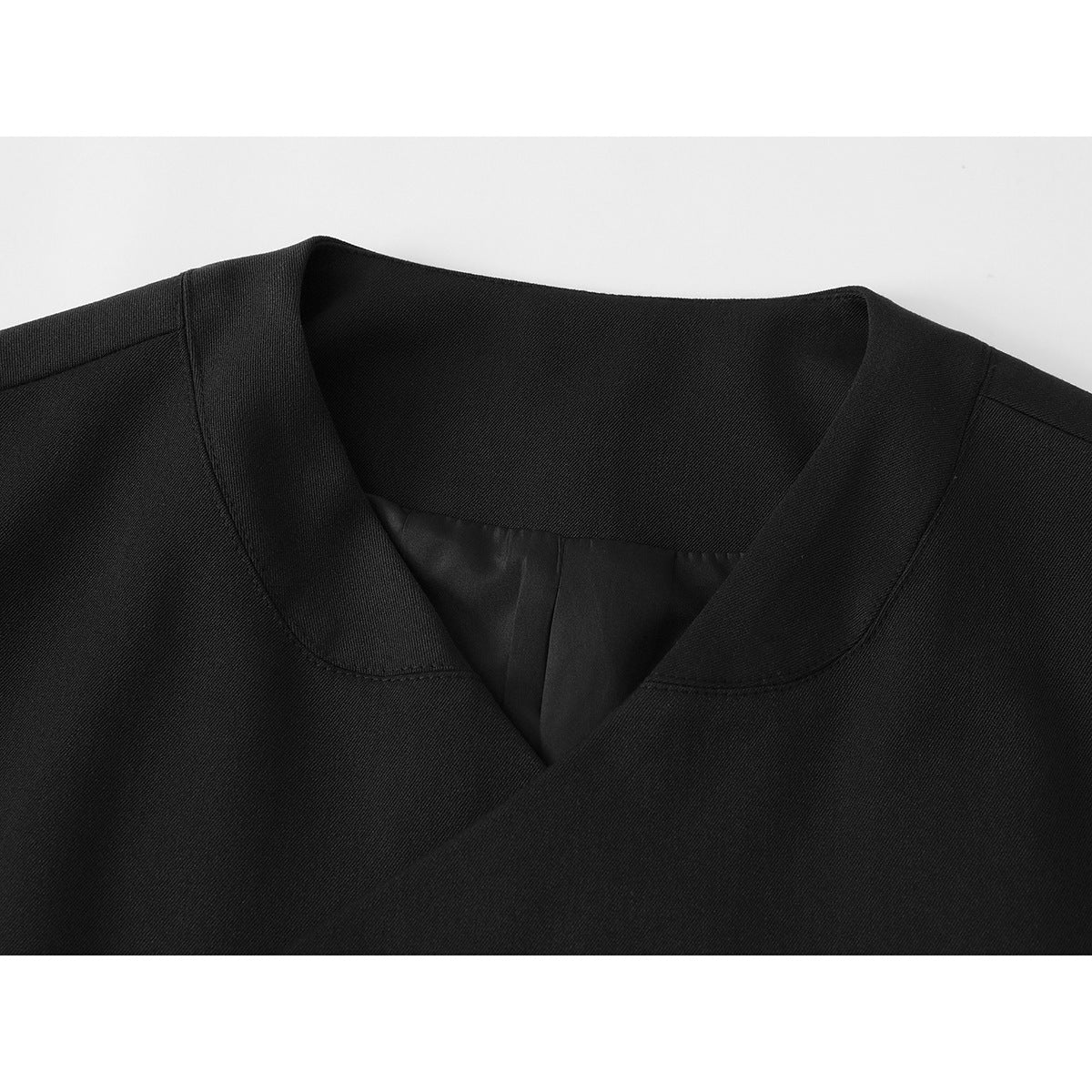 Close-up of a black jacket's notched wrap neckline and inner lining.