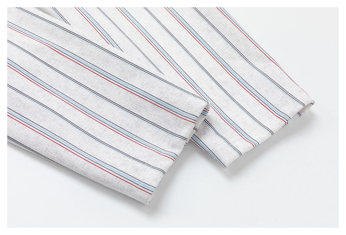 Close-up of overlapping edges of light gray fabric with red, blue, and dark stripes.