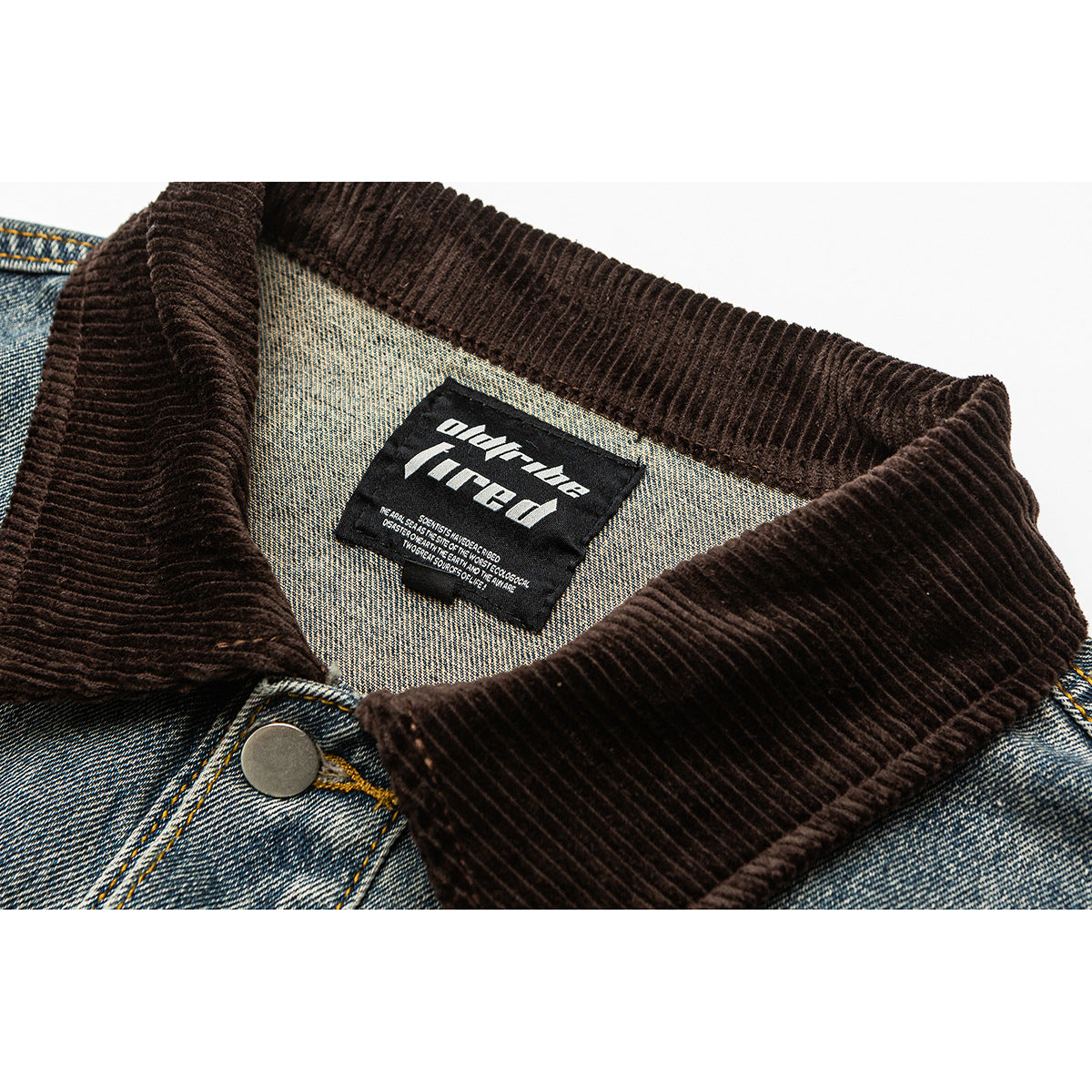 Close-up of a blue denim jacket’s dark brown corduroy collar, metal button and sewn neck label.