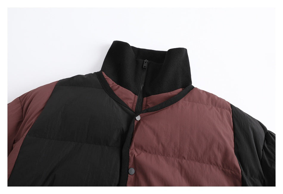 Close-up of a two-tone black and muted burgundy padded jacket with a ribbed high collar, zipper and snap-front trim.