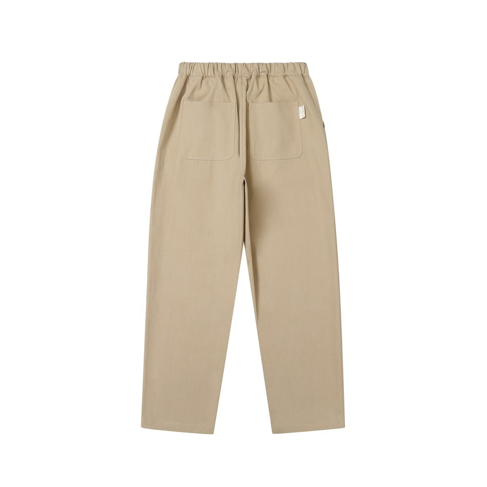 Back view of tan pants with an elastic waistband, two patch pockets, and straight legs.