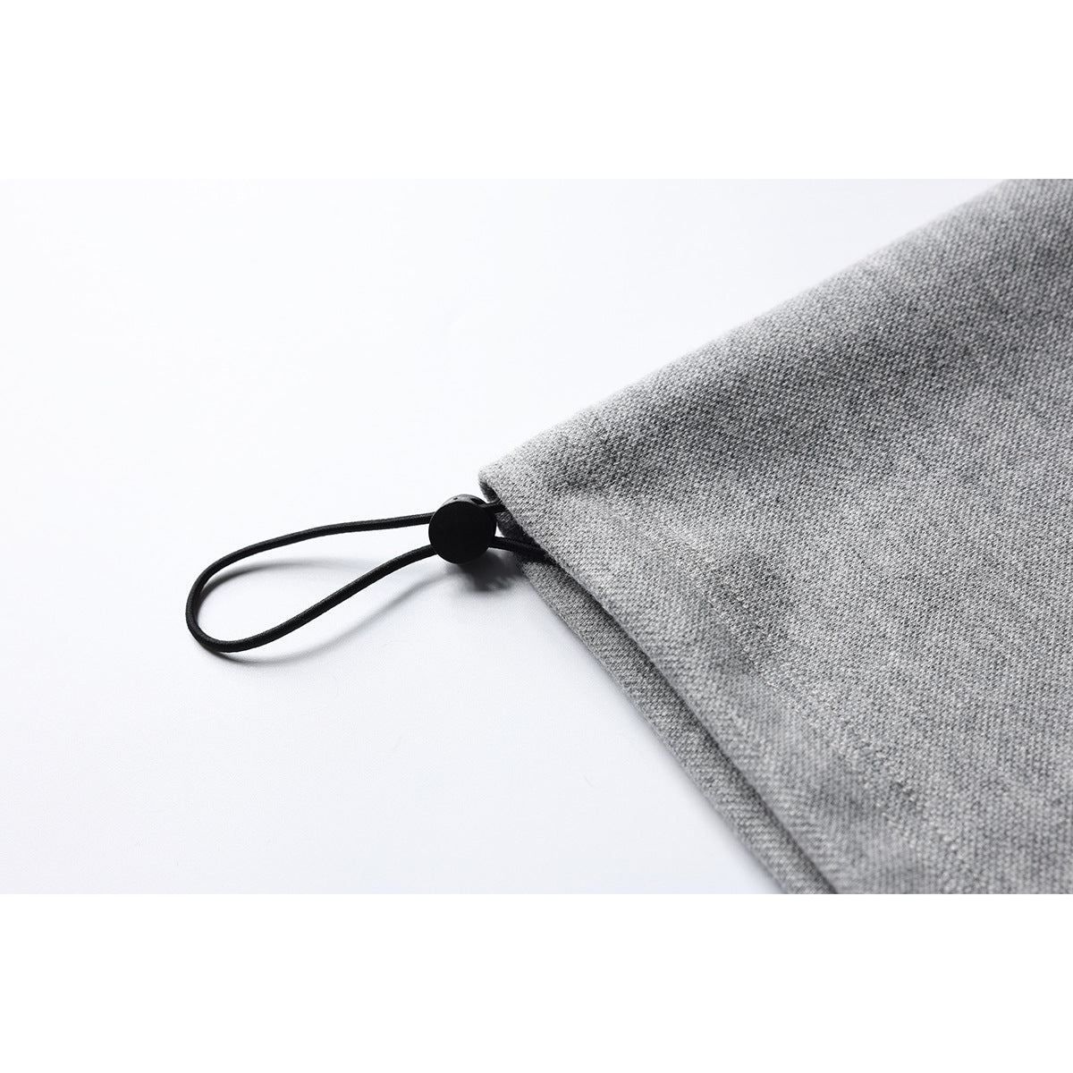 Close-up of a gray shirt hem with a black elastic loop and round toggle.