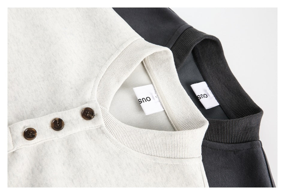 Close-up of light gray and charcoal sweatshirts showing their ribbed collars and sewn-in neck labels.