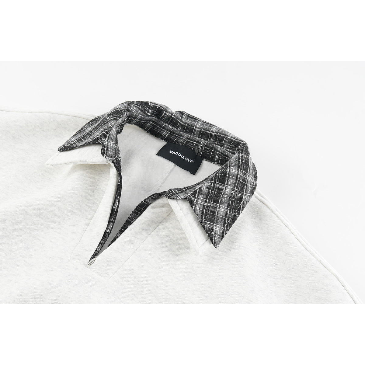 Close-up of a light gray sweatshirt with a black-and-white plaid collar and sewn neck label.