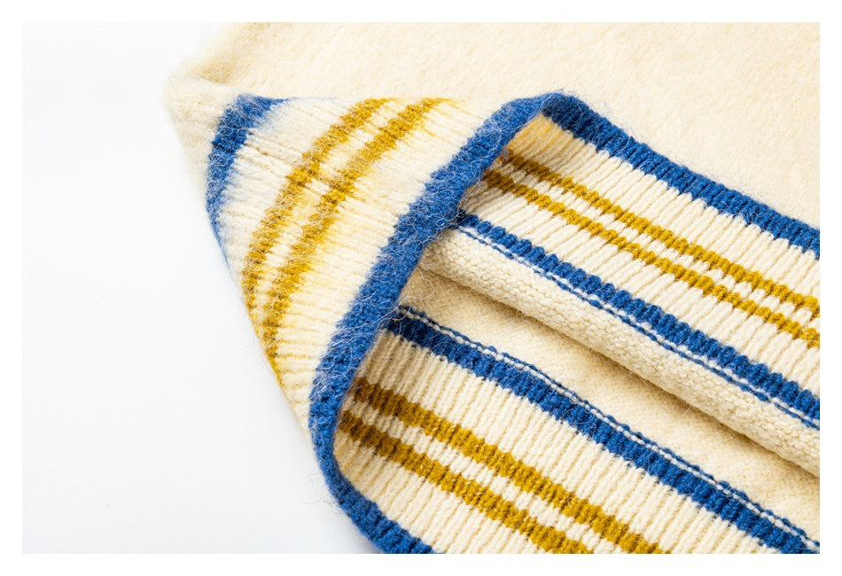Close-up of the vest's cream ribbed hem with blue and mustard stripes and fuzzy knit fabric.