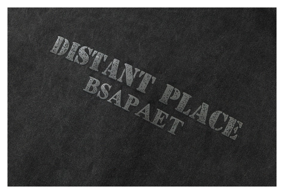 Close-up of distressed light lettering printed diagonally on charcoal fabric.