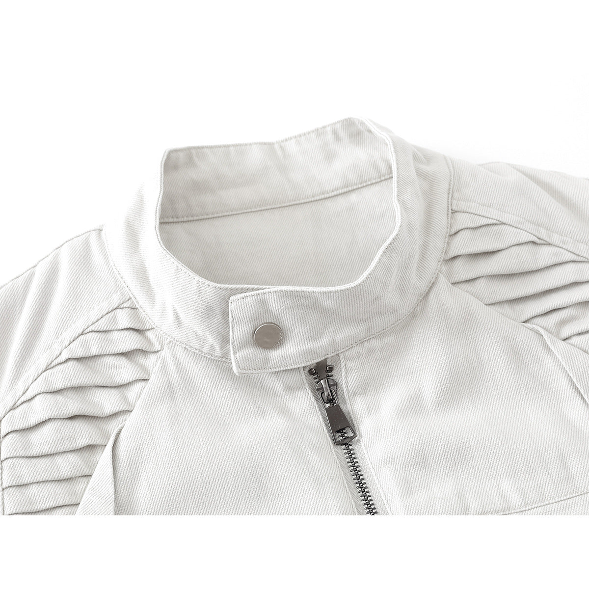 Close-up of an off-white jacket's stand collar, snap tab, center zipper, and pleated shoulder panels.