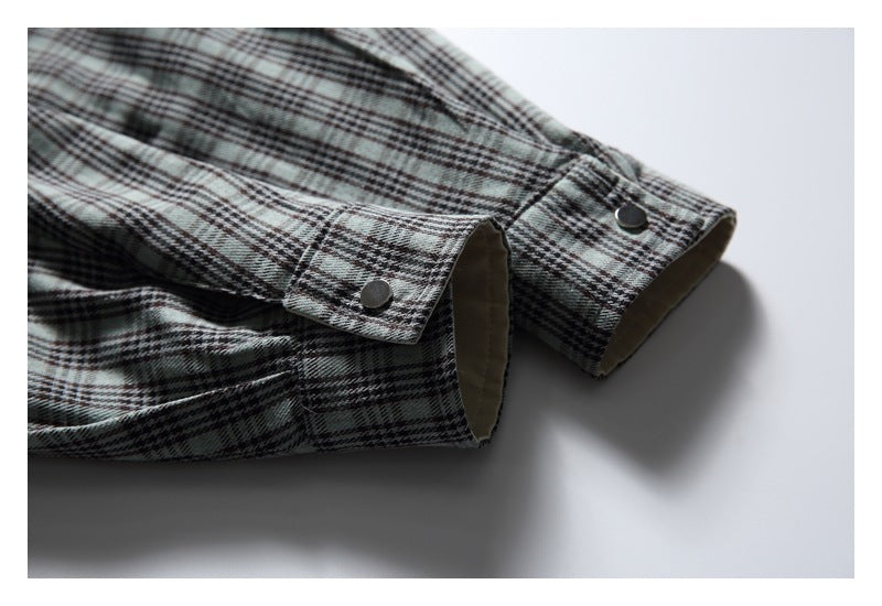 Close-up of two gray plaid sleeve cuffs with metal snaps and beige lining.