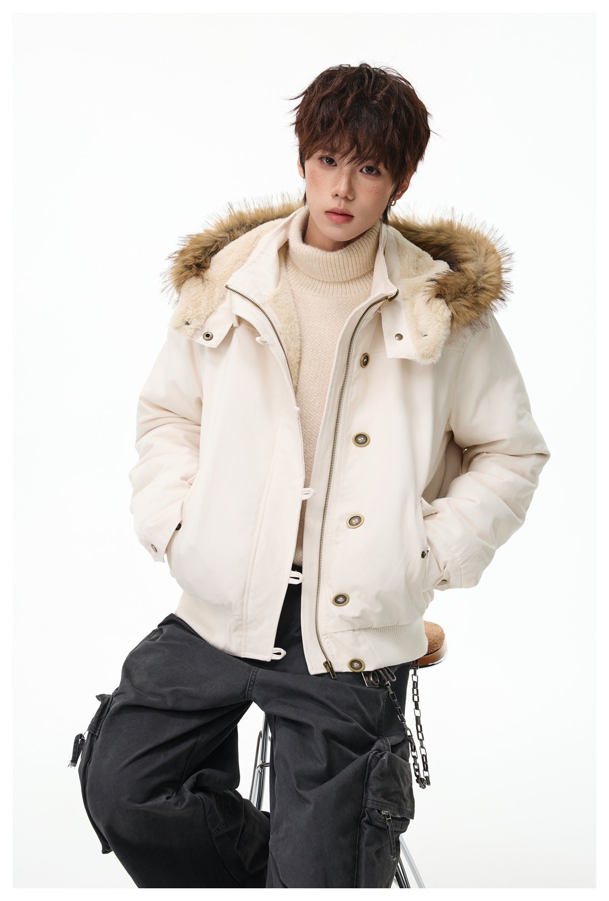 Model wearing an open ivory hooded jacket with tan faux-fur trim, layered over a cream turtleneck.