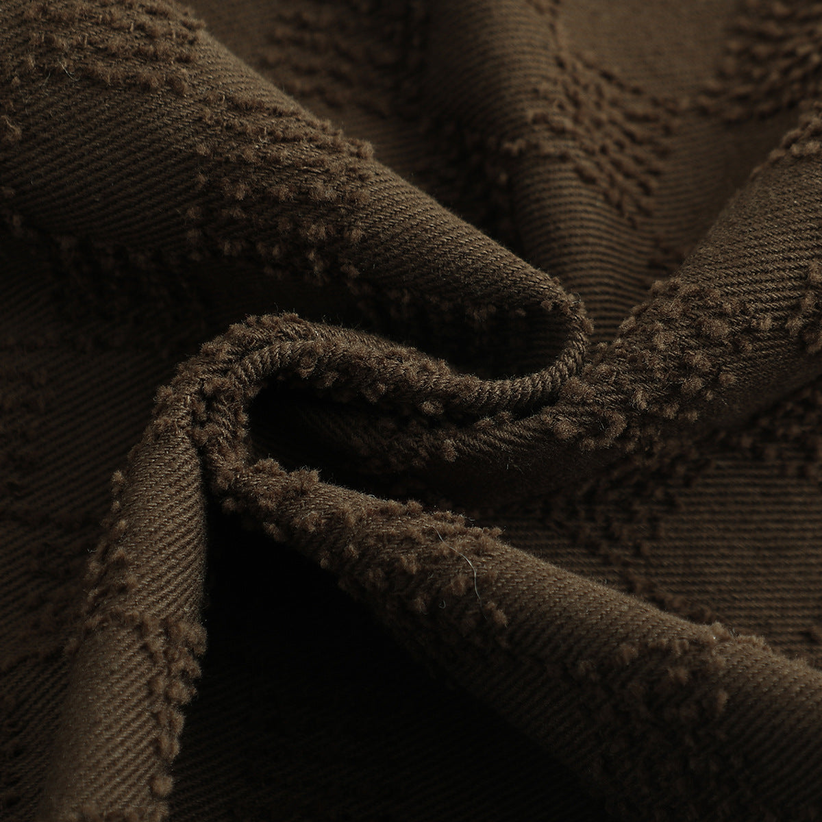 Macro view of the brown shorts’ raised checker pattern and textured fabric surface.